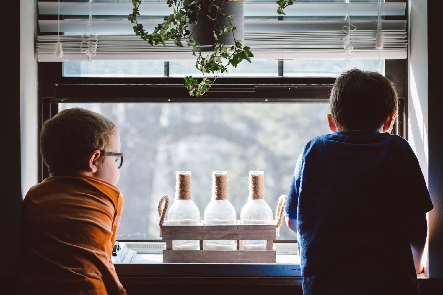 two young boys looking out kitchen window together