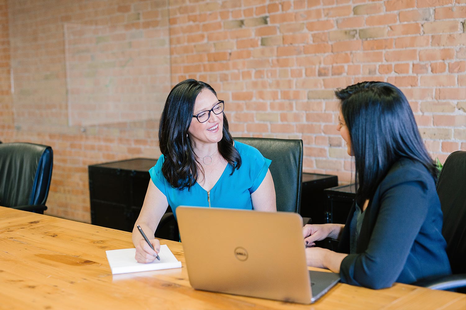 two professional women sit down at wooden desk for friendly meeting